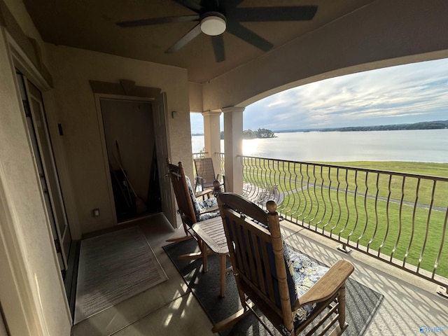 balcony with a water view and a ceiling fan