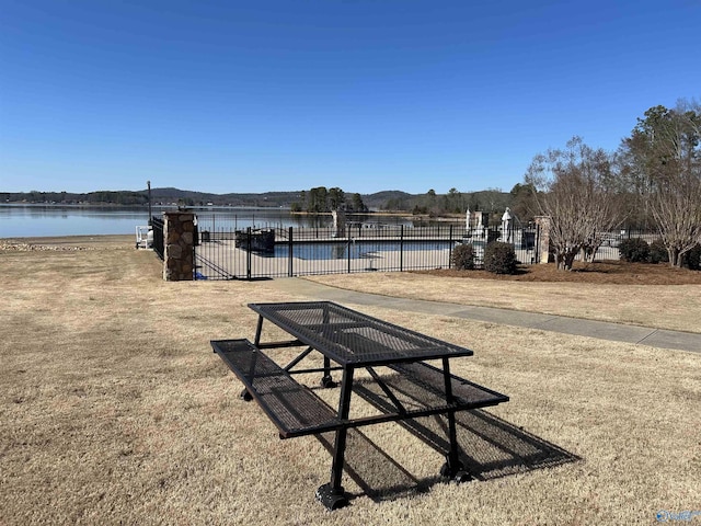 view of home's community with a water view and fence