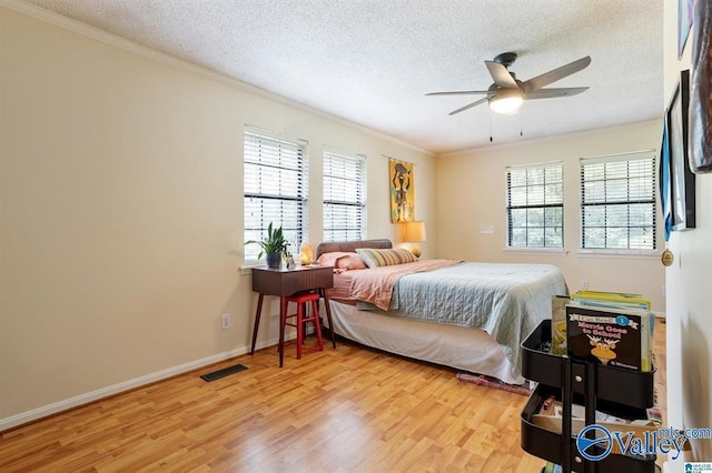 bedroom with light hardwood / wood-style floors, multiple windows, crown molding, and ceiling fan