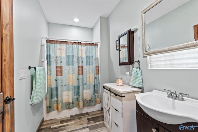 bathroom featuring shower / bathtub combination with curtain, wood finished floors, and vanity