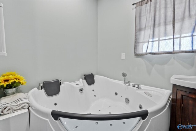 full bathroom with a jetted tub and vanity