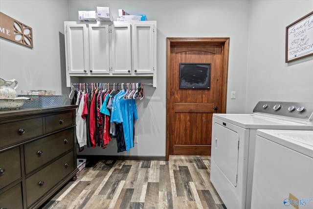 laundry area featuring light wood-style floors, washer and clothes dryer, and cabinet space