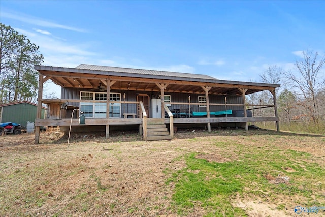 view of front of house featuring metal roof, board and batten siding, an outdoor structure, and a ceiling fan