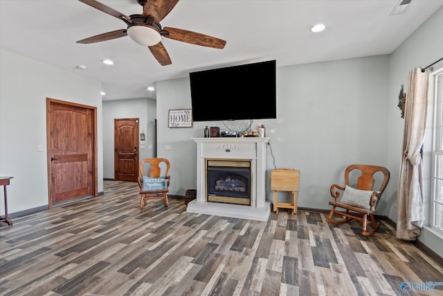 sitting room with a fireplace with raised hearth, wood finished floors, visible vents, and baseboards