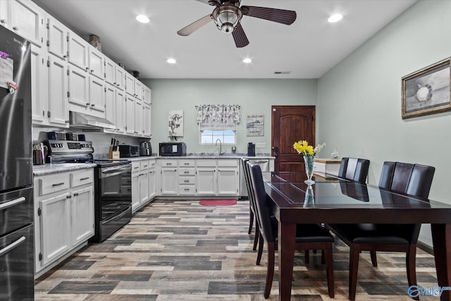 kitchen with electric range oven, white cabinets, a sink, black microwave, and exhaust hood
