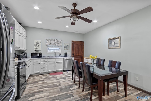 kitchen with black appliances, white cabinetry, light wood-style floors, and a sink