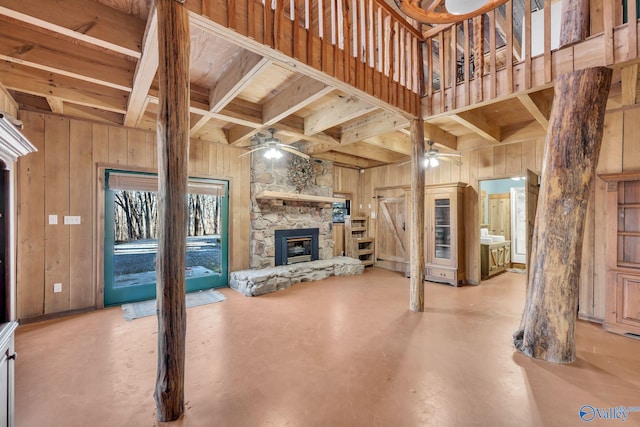 136 Higdon Rd, Falkville, AL 35622 - unfurnished living room with a ceiling fan, wooden walls, a fireplace, finished concrete flooring, and a wooden ceiling with exposed beams