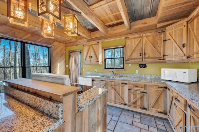 136 Higdon Rd, Falkville, AL 35622 - kitchen featuring a wooden ceiling with exposed beams, white microwave, stone tile flooring, light brown cabinetry, and light stone counters
