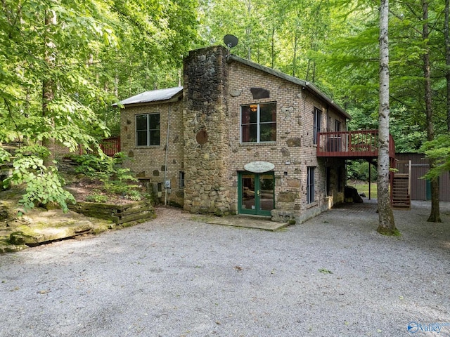 136 Higdon Rd, Falkville, AL 35622 - tudor-style house featuring a deck, stairway, french doors, gravel driveway, and brick siding