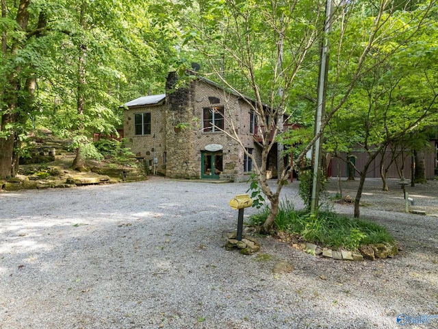 136 Higdon Rd, Falkville, AL 35622 - view of front facade with a chimney, stone siding, brick siding, and a wooded view