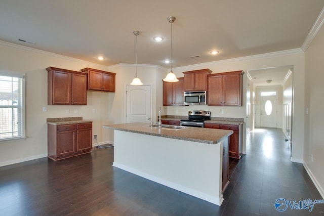 kitchen featuring appliances with stainless steel finishes, dark wood-type flooring, sink, a center island with sink, and hanging light fixtures