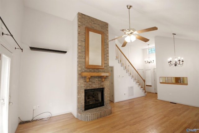 209 Leslie Ln, Harvest, AL 35749 - unfurnished living room with high vaulted ceiling, wood finished floors, a ceiling fan, a brick fireplace, and stairs