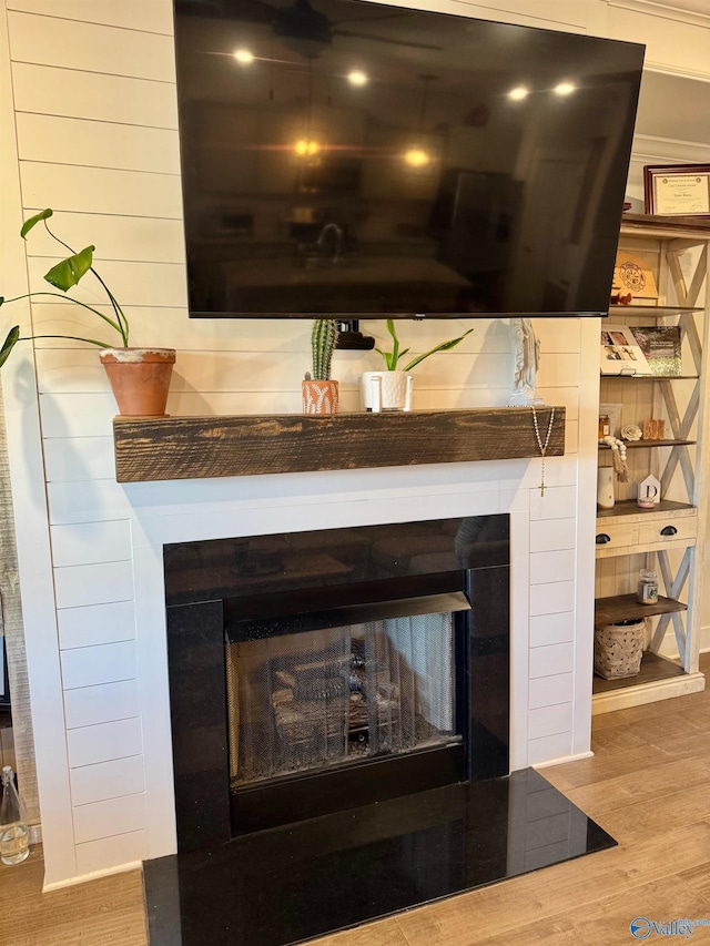 details featuring wood finished floors, wooden walls, and a fireplace with raised hearth