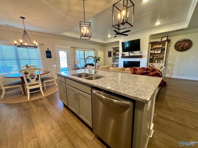 kitchen with dishwasher, a fireplace, a tray ceiling, and a sink