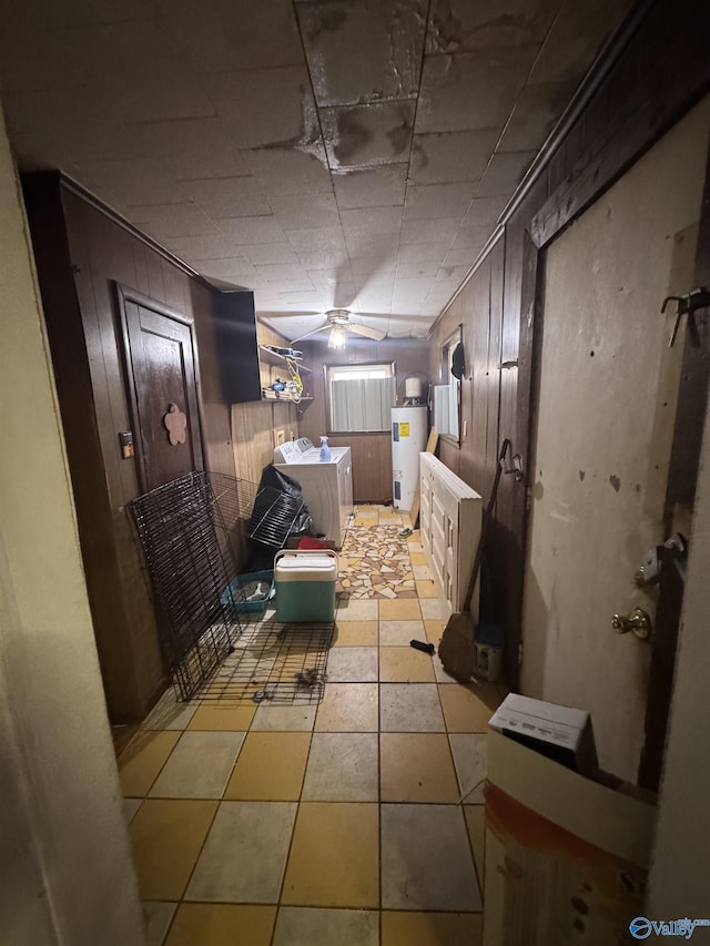 bathroom featuring ceiling fan, washing machine and clothes dryer, wooden walls, and water heater