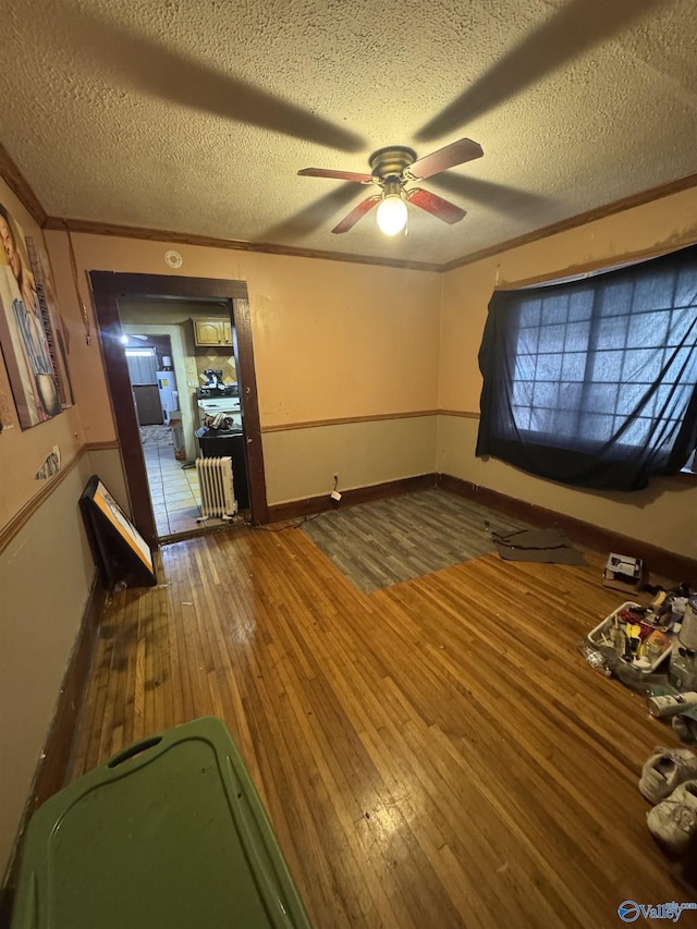 interior space with crown molding, hardwood / wood-style floors, ceiling fan, and a textured ceiling