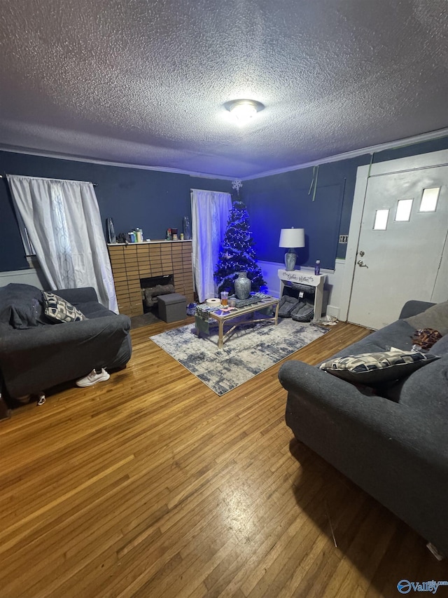 living room featuring hardwood / wood-style flooring, a brick fireplace, and a textured ceiling