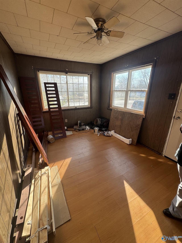 spare room with hardwood / wood-style floors, wooden walls, and ceiling fan