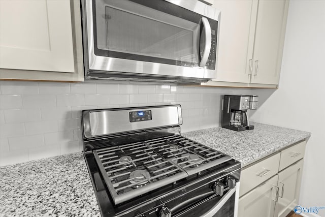 kitchen featuring appliances with stainless steel finishes, light stone countertops, and tasteful backsplash