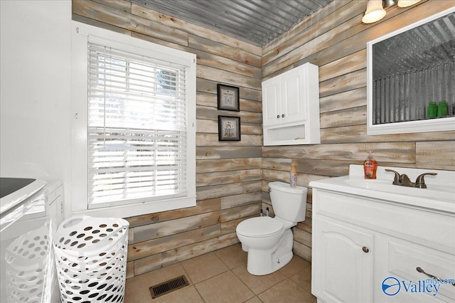 bathroom featuring visible vents, toilet, tile patterned flooring, vanity, and wood walls