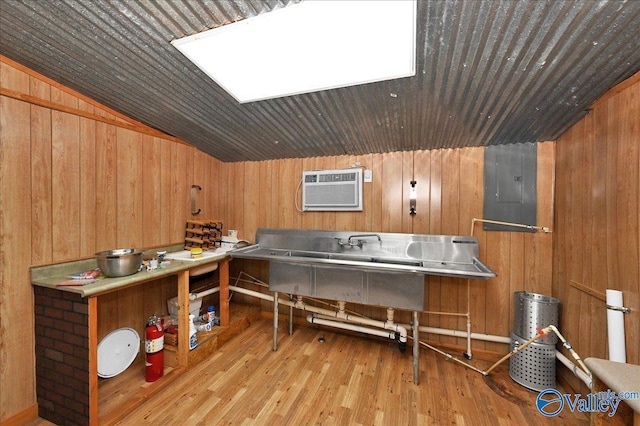 kitchen featuring wooden walls, electric panel, an AC wall unit, and wood finished floors