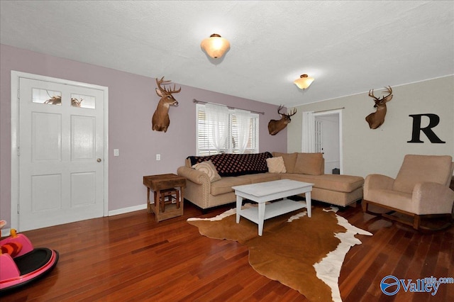 living area featuring a textured ceiling, wood finished floors, and baseboards