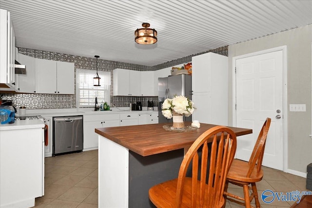 kitchen with light tile patterned floors, white cabinets, appliances with stainless steel finishes, backsplash, and pendant lighting