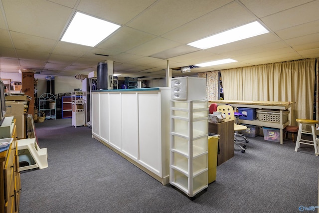 basement featuring a drop ceiling and dark colored carpet