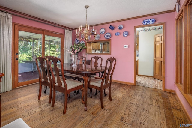 dining space with light hardwood / wood-style floors, a textured ceiling, ornamental molding, and a chandelier