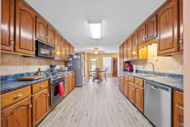 kitchen with sink, ceiling fan, backsplash, stainless steel appliances, and light hardwood / wood-style floors