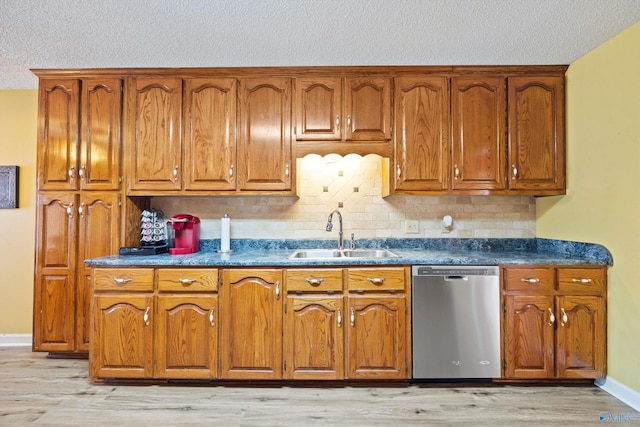 kitchen with sink, tasteful backsplash, a textured ceiling, stainless steel dishwasher, and light hardwood / wood-style floors