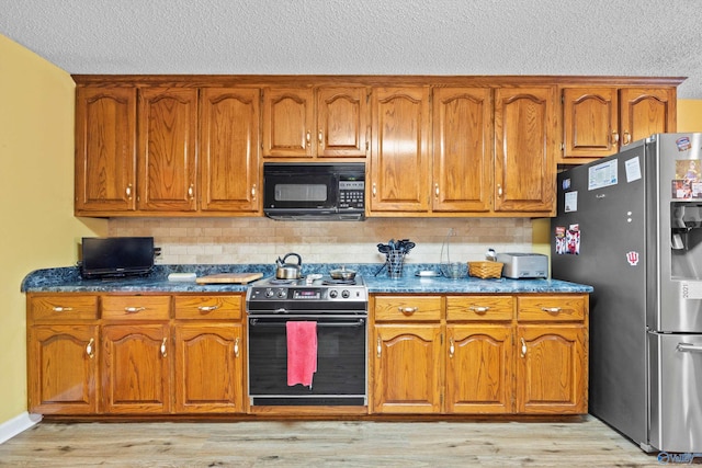 kitchen featuring backsplash, light hardwood / wood-style flooring, and black appliances