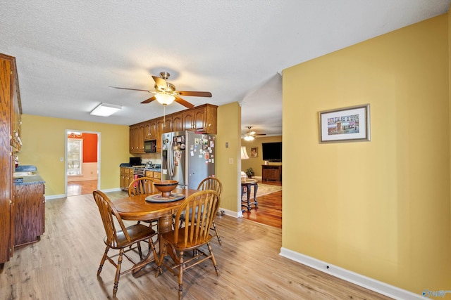 dining area featuring ceiling fan, a textured ceiling, and light wood-type flooring