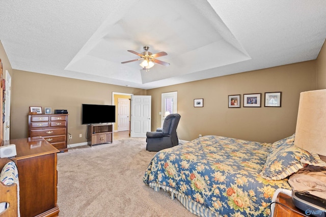 carpeted bedroom with ceiling fan, a tray ceiling, and a textured ceiling