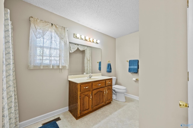 bathroom with vanity, toilet, and a textured ceiling