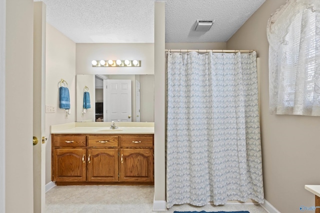 bathroom with vanity, a textured ceiling, and walk in shower