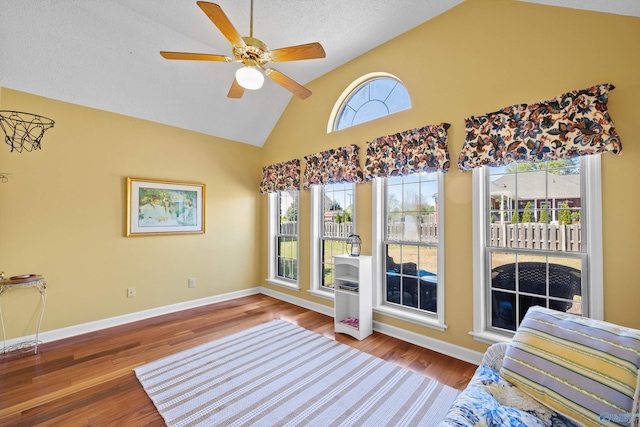 interior space with ceiling fan, wood-type flooring, high vaulted ceiling, and a textured ceiling