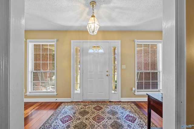 foyer entrance with wood-type flooring and a textured ceiling