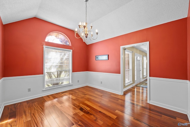 unfurnished room with plenty of natural light, dark hardwood / wood-style flooring, and vaulted ceiling