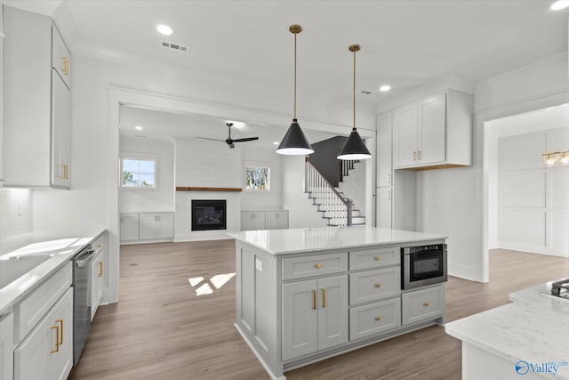 kitchen featuring ceiling fan, a center island, dishwasher, pendant lighting, and a fireplace