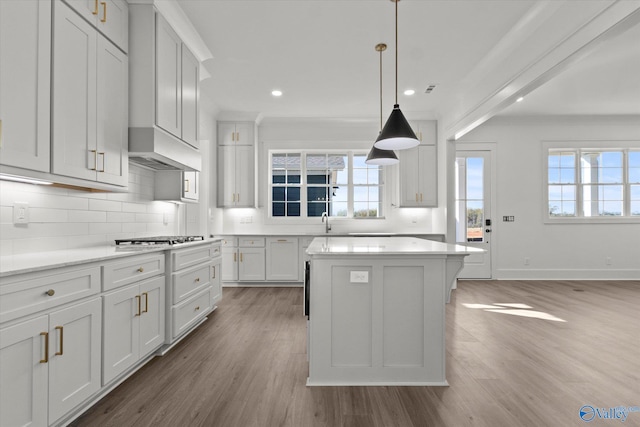 kitchen featuring white cabinets, light wood-type flooring, a center island, and hanging light fixtures