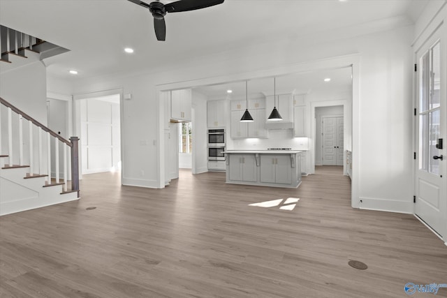 unfurnished living room with light wood-type flooring, ceiling fan, and crown molding