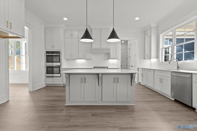 kitchen featuring decorative backsplash, a kitchen island, white cabinets, and appliances with stainless steel finishes