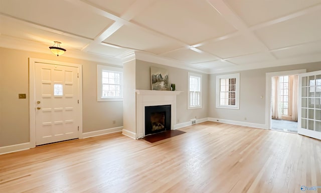 unfurnished living room featuring a healthy amount of sunlight, coffered ceiling, and light wood-type flooring