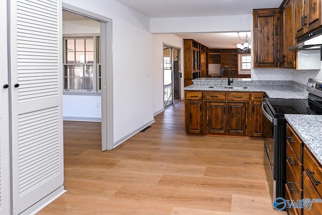 kitchen with sink, electric range oven, backsplash, light stone countertops, and light wood-type flooring