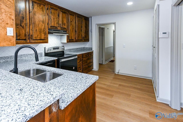 kitchen with sink, decorative backsplash, stainless steel range with electric stovetop, light stone countertops, and light wood-type flooring