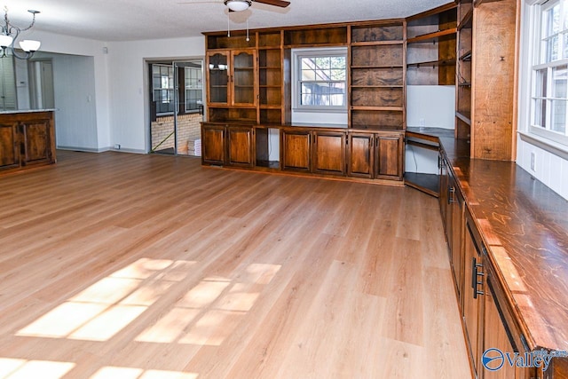 kitchen with butcher block counters, ceiling fan with notable chandelier, pendant lighting, and light wood-type flooring