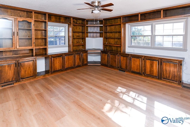 unfurnished living room featuring ceiling fan, light hardwood / wood-style floors, and a textured ceiling