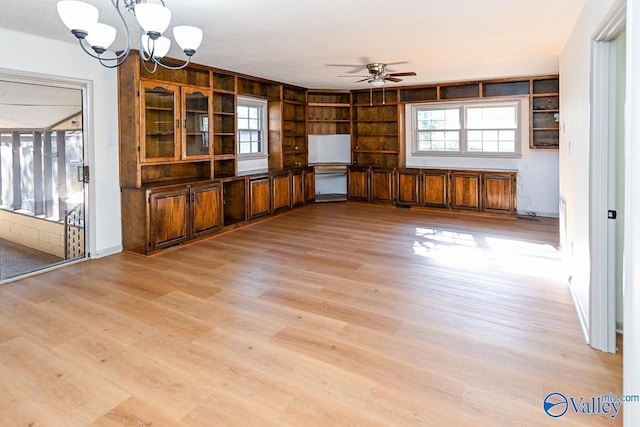 unfurnished living room with ceiling fan with notable chandelier, a textured ceiling, and light hardwood / wood-style floors