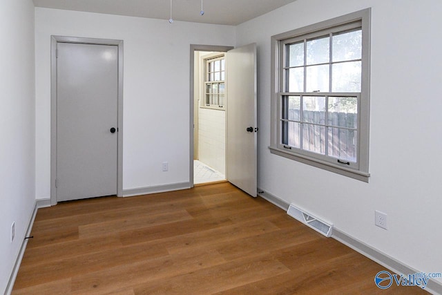 unfurnished bedroom with hardwood / wood-style floors and ensuite bath